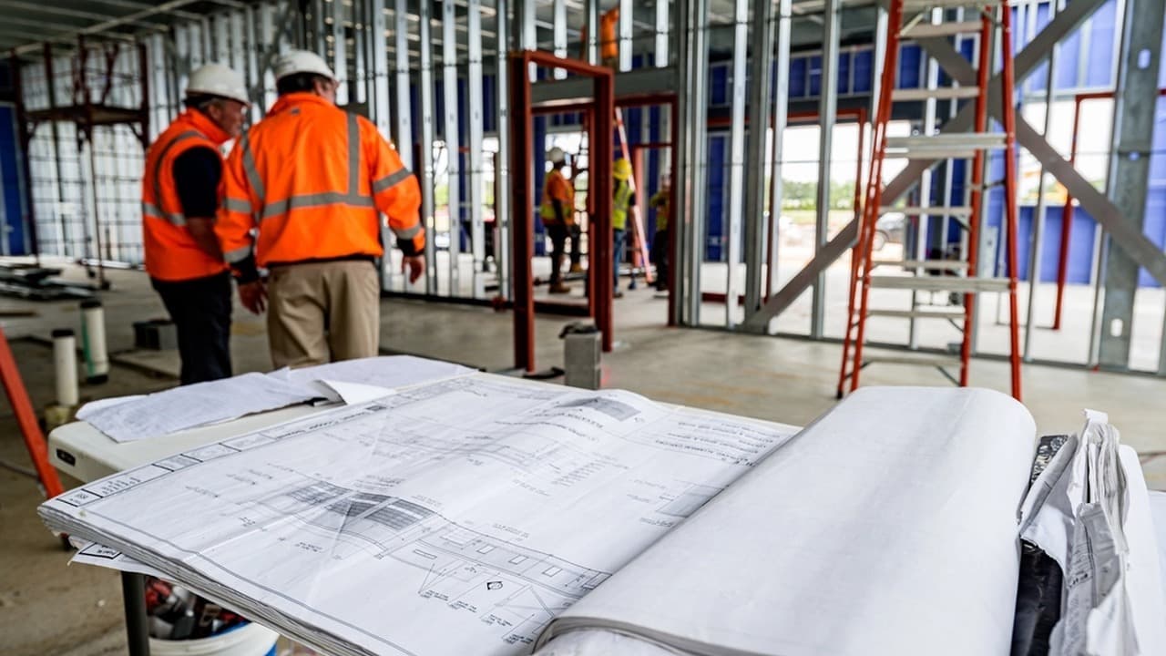 Two project leaders reviewing plans at a construction site.