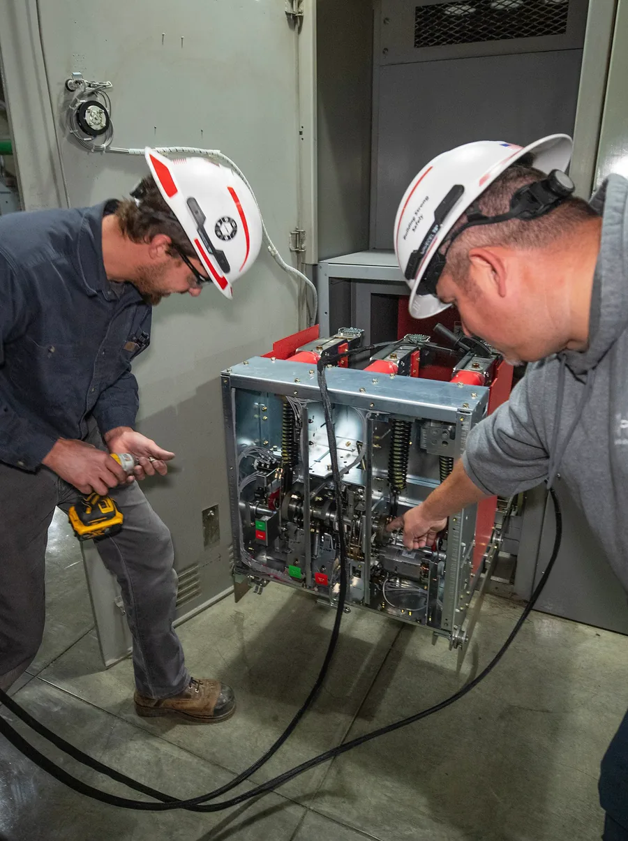Electricians servicing medium-voltage switchgear
